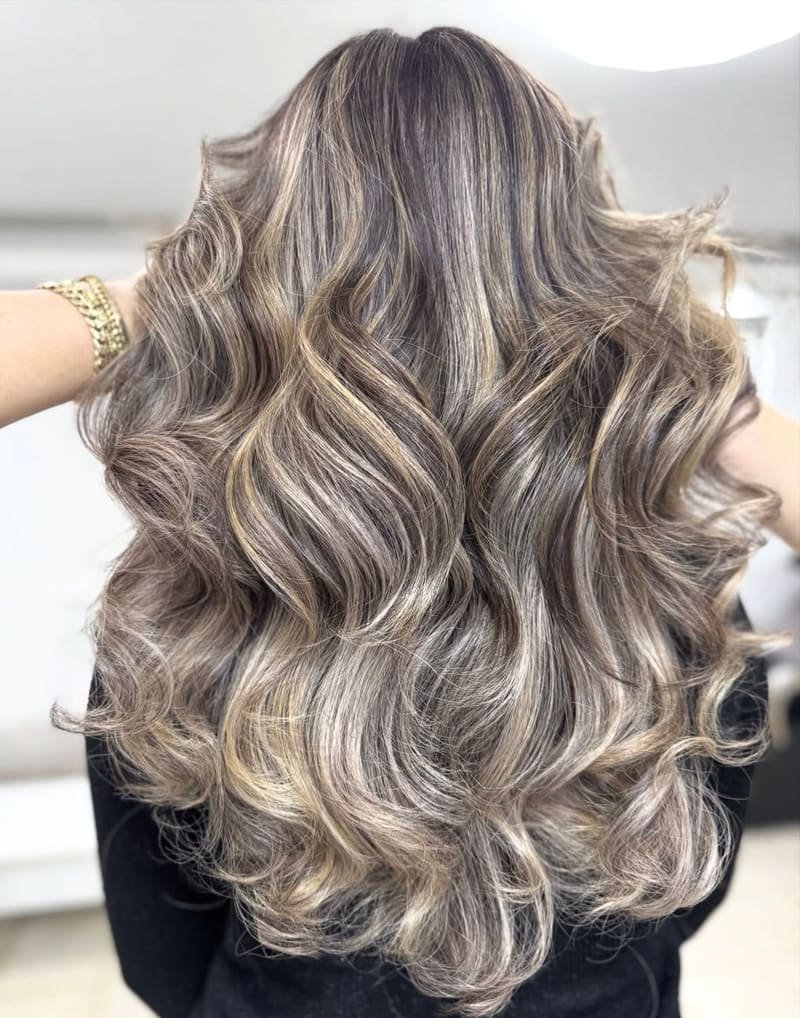Smoky ash highlights over a darker base, set in full, voluminous curls